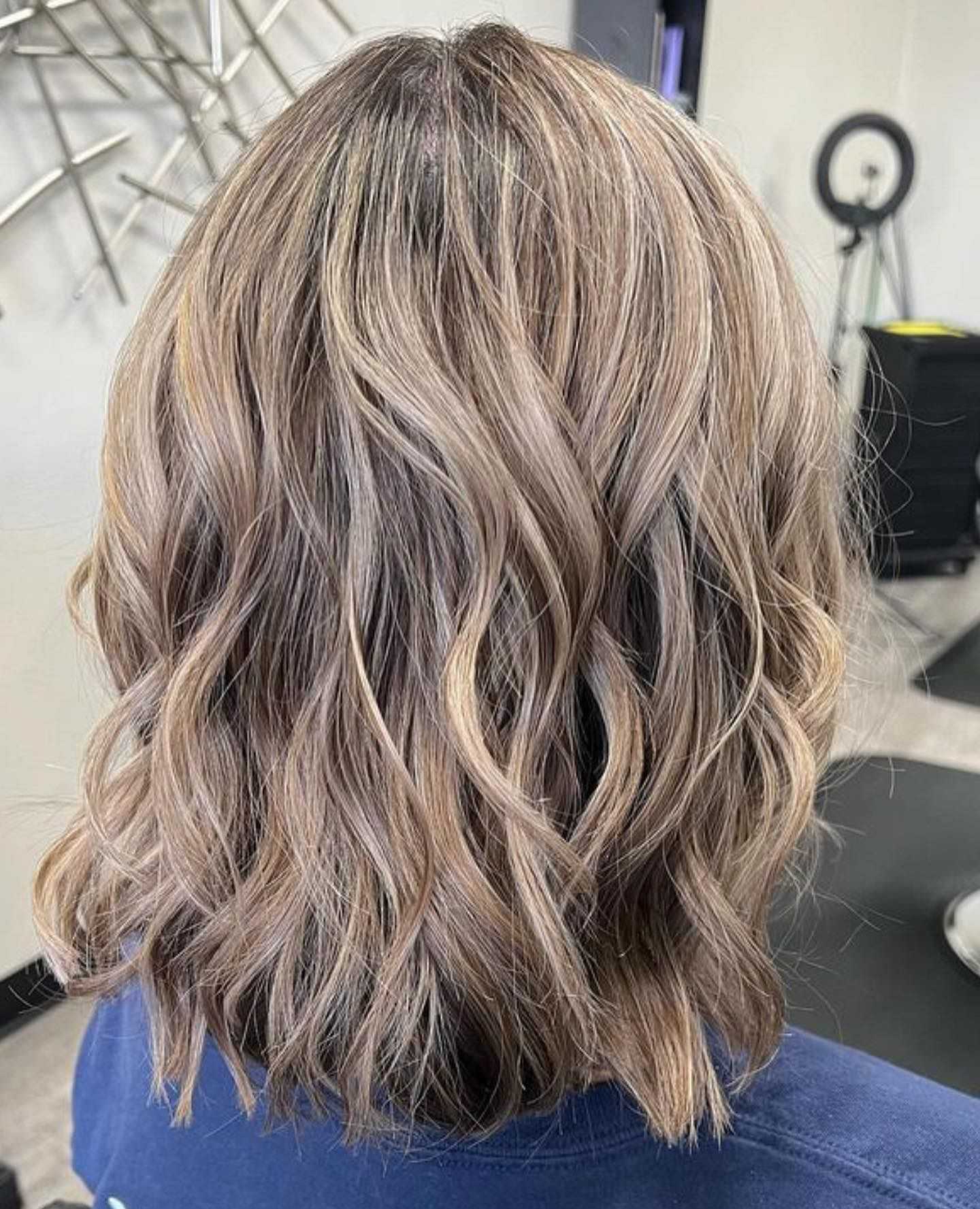 Wavy blonde hair with subtle highlights from the back, styled in loose beachy waves.