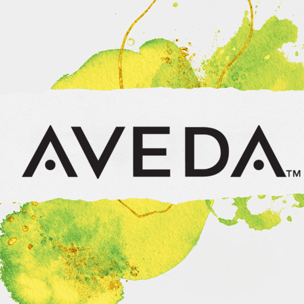 Aveda logo with artistic yellow and green paint splashes in the background.